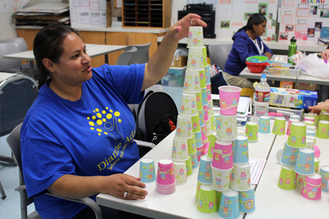 Student instructor builds a tower with several small paper cups.