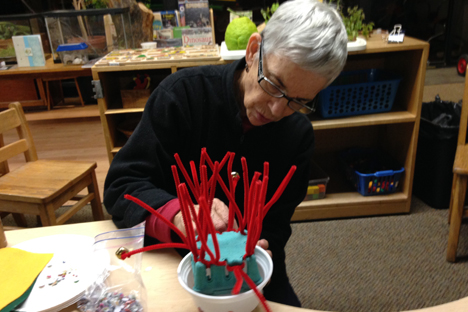 Student instructor uses pipe cleaners and paper cups to construct a creative art piece.